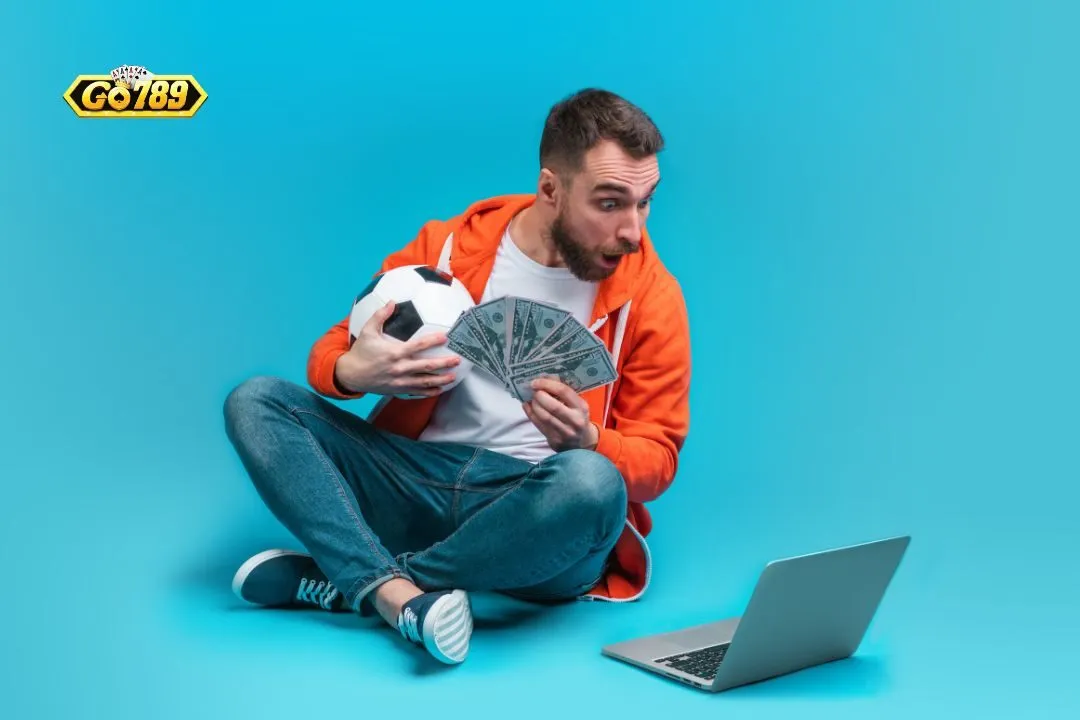 Hội viên cầm tiền thưởng ngồi trước laptop sau khi đăng ký GO789